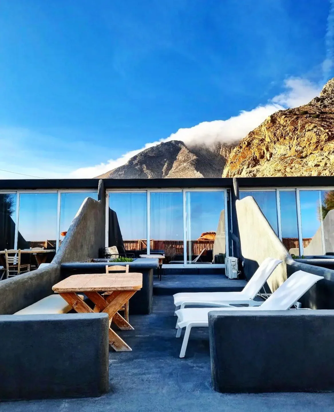 Demilmar restaurant patio with lounge chairs and mountain view, overlooking the city.